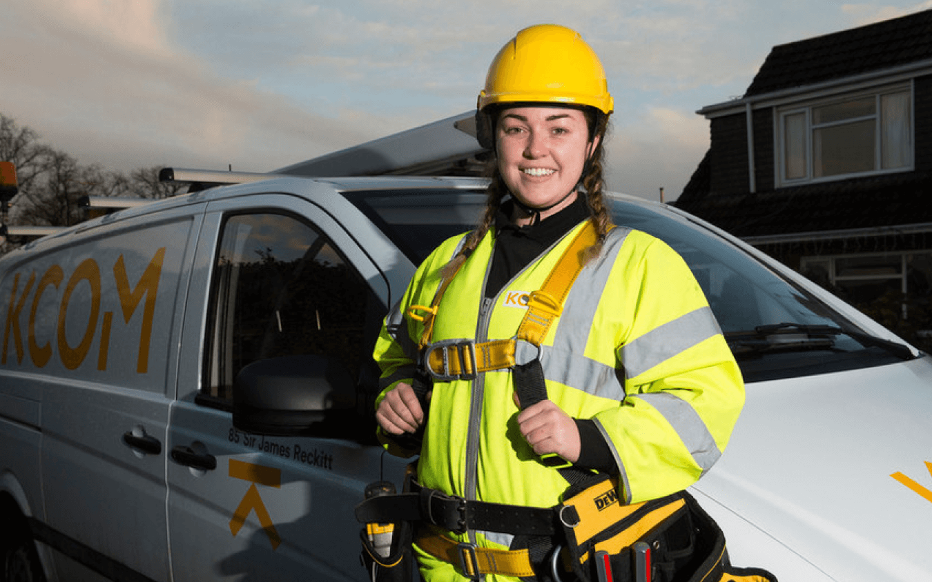 The image shows an female engineer standing outside her van.